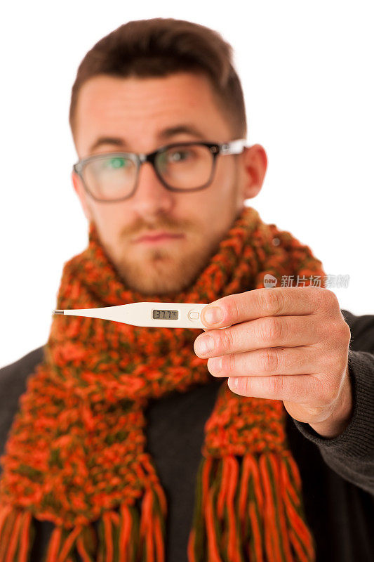 一名患流感和发烧的男子裹在围巾里，拿着体温计。