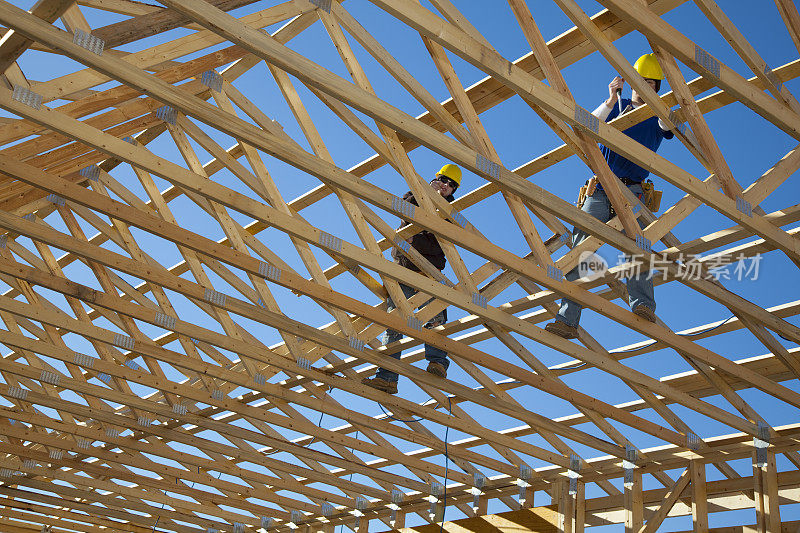 建筑施工;两名男子在搭建屋顶桁架