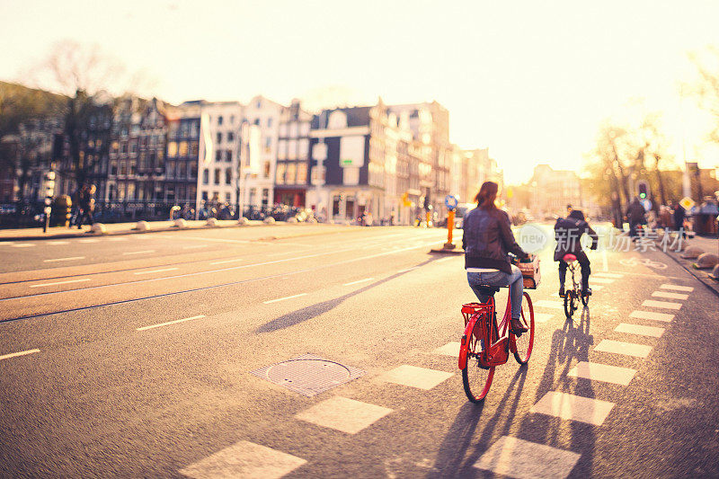 日落时分，人们在阿姆斯特丹的街道上骑自行车