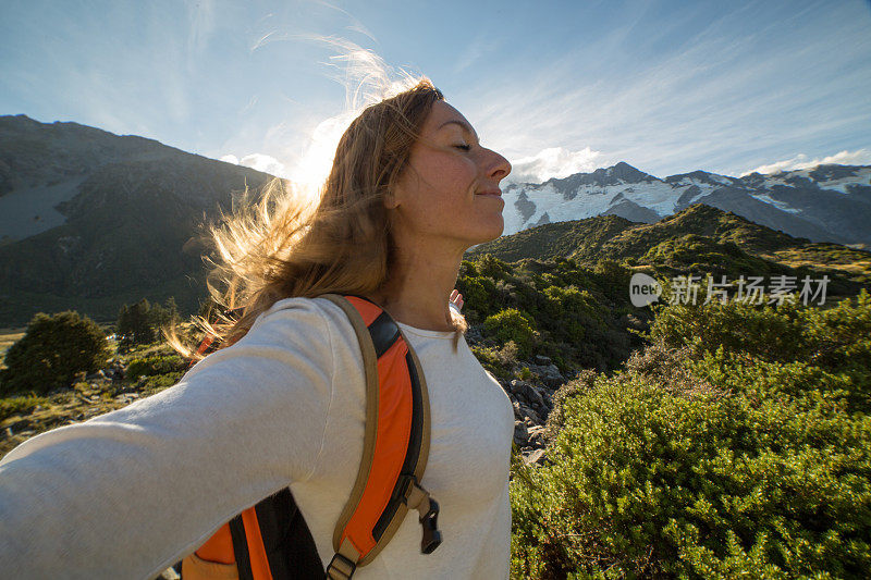 女性在山顶上举起双臂迎接日出的肖像