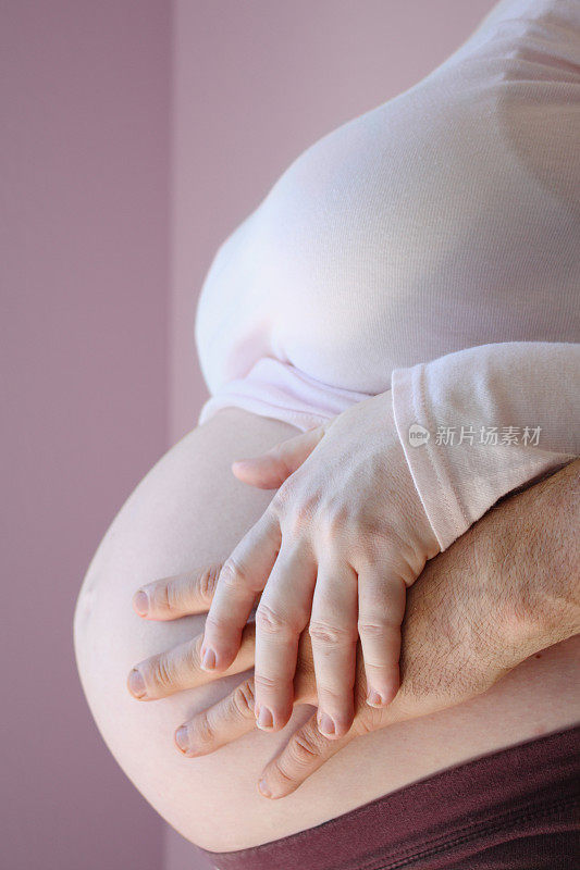 男人和女人的手在怀孕的肚子