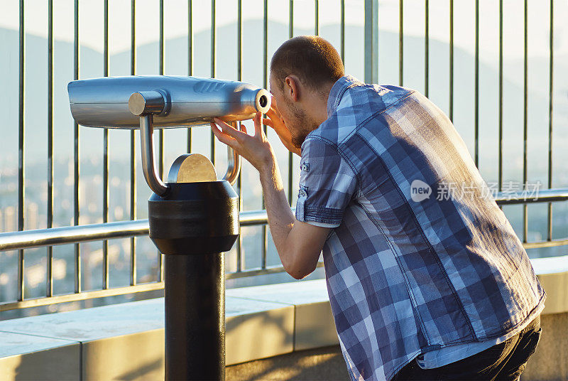 愉快的年轻游客使用望远镜塔观景台
