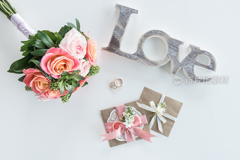顶视图的金婚戒，装饰信封，美丽的花束和爱的象征，婚礼邀请卡的概念