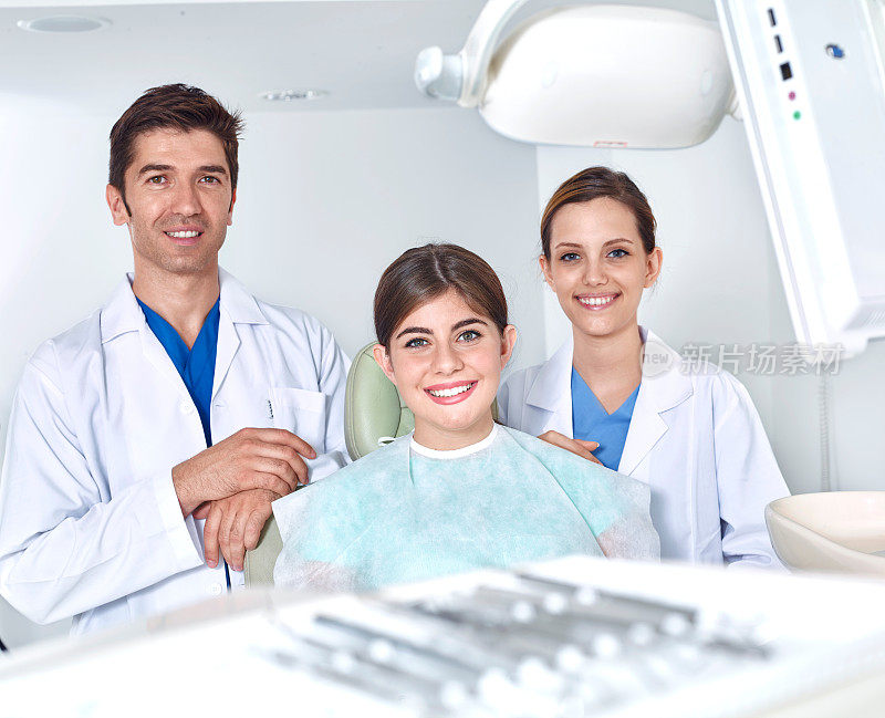 牙医、助理和对着镜头微笑的年轻女子