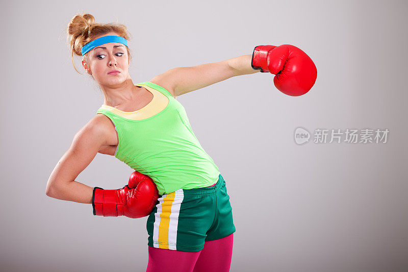 有趣的拳击女孩摆着红色拳击手套的姿势
