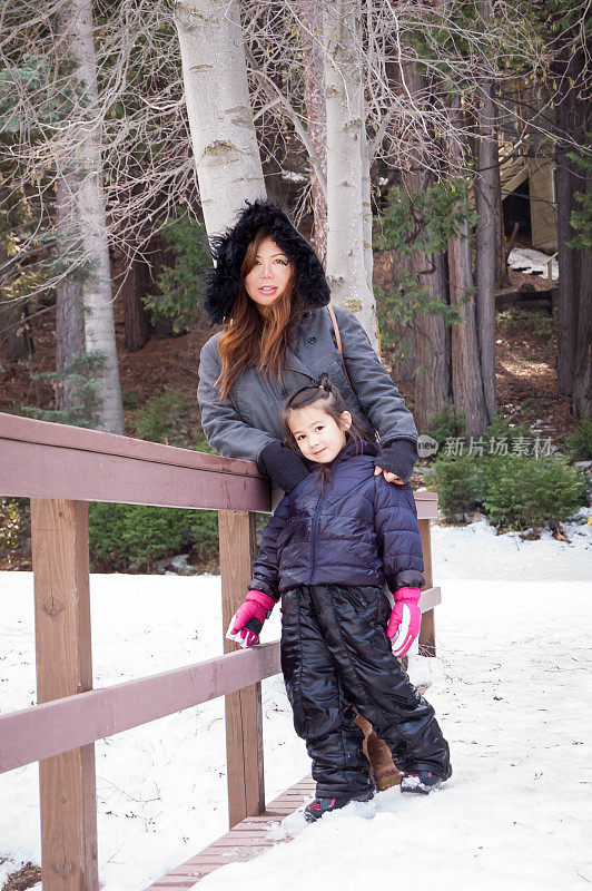 漂亮的母亲和女儿穿着暖和的雪