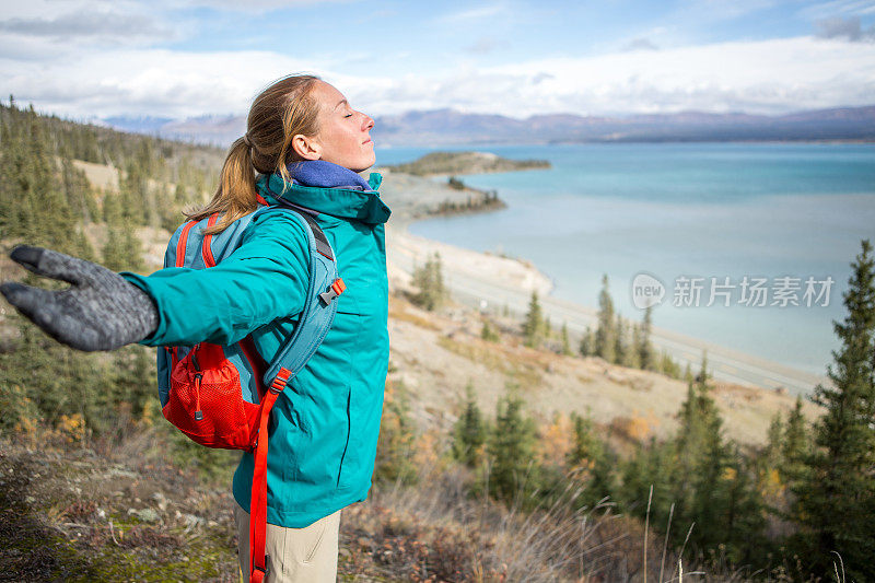 欢呼的女性徒步旅行者伸出手臂俯瞰湖面