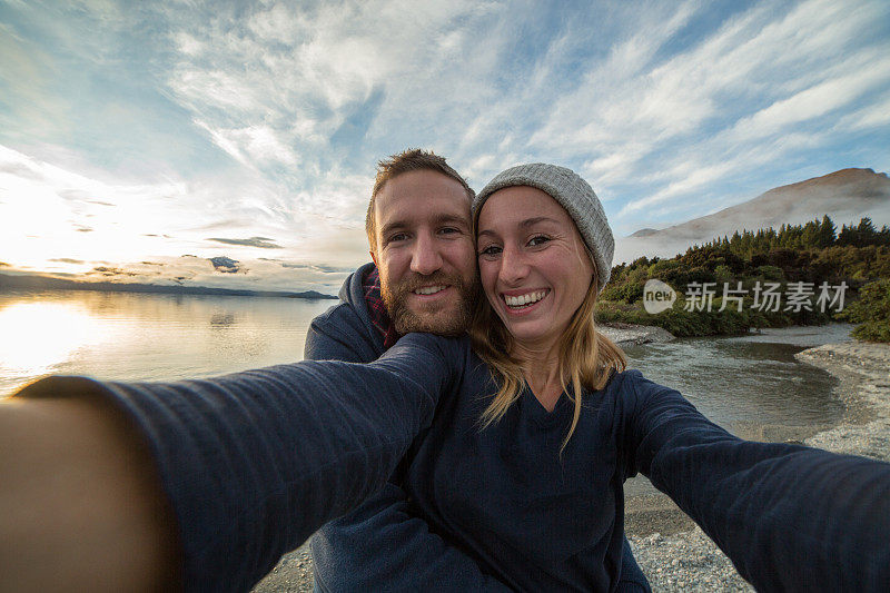 日出时分，一对年轻夫妇在湖边自拍