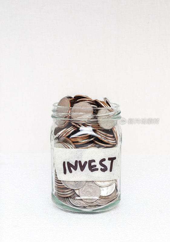 装有钱的玻璃罐子，白色背景上的标签上写着“投资”