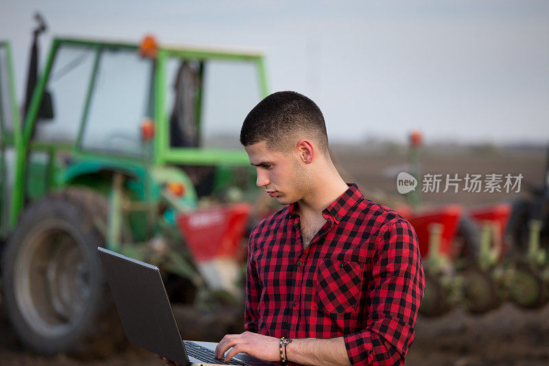 农民把笔记本电脑放在农用设备前