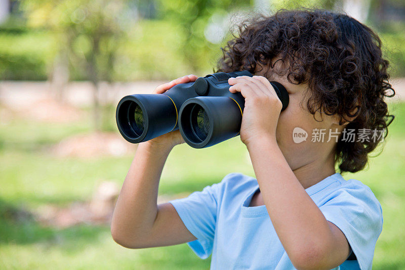 小男孩拿着望远镜在公园里