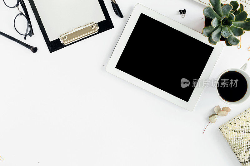 白色的写字板，键盘，记事本，玻璃杯，多肉和咖啡杯。办公室桌子桌子上。俯视图