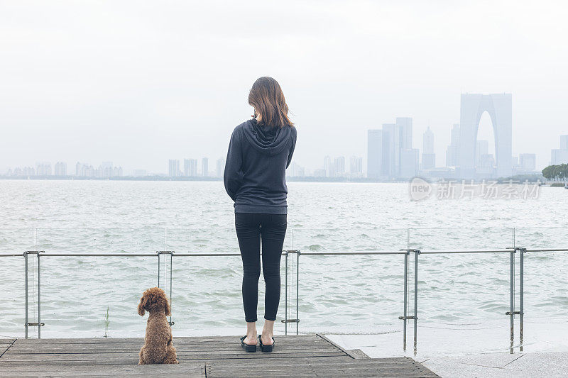 后视图的女人站在码头和她的宠物坐在一边