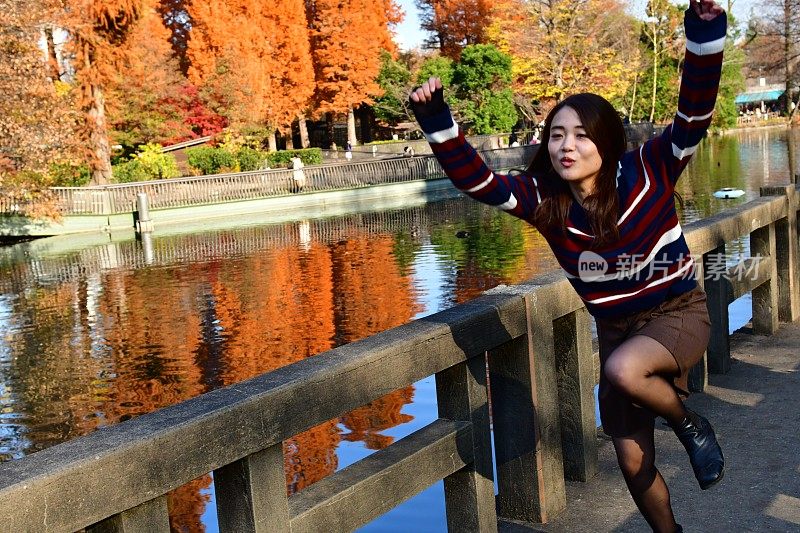 年轻的日本女子在东京的猪城公园的桥上跑和跳