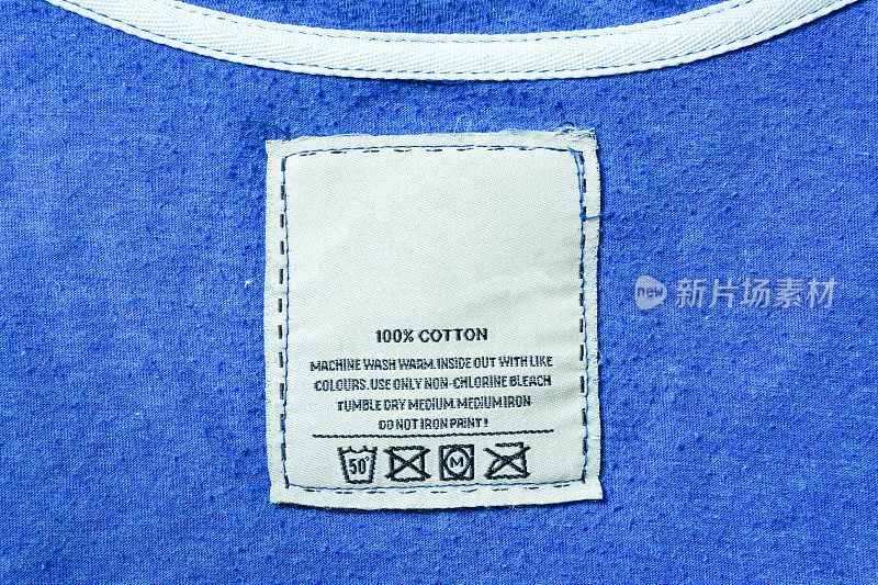 服装标签与洗衣说明，人阅读服装标签显示洗涤说明，衣服，家政概念的特写。