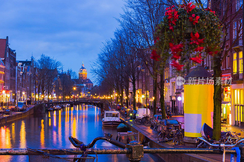 阿姆斯特丹运河和桥的夜间照明，有典型的荷兰房屋，船只和自行车。
