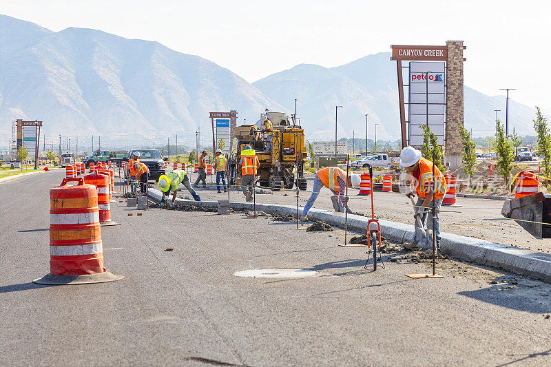 几名道路建筑工人在犹他州西班牙福克铺设的街道上清理中心介质