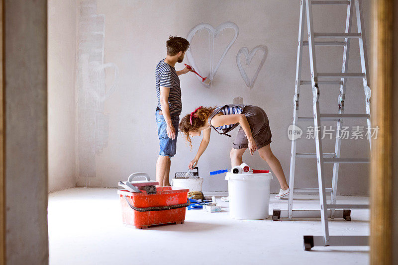 一对在家里墙上画心形的夫妇。