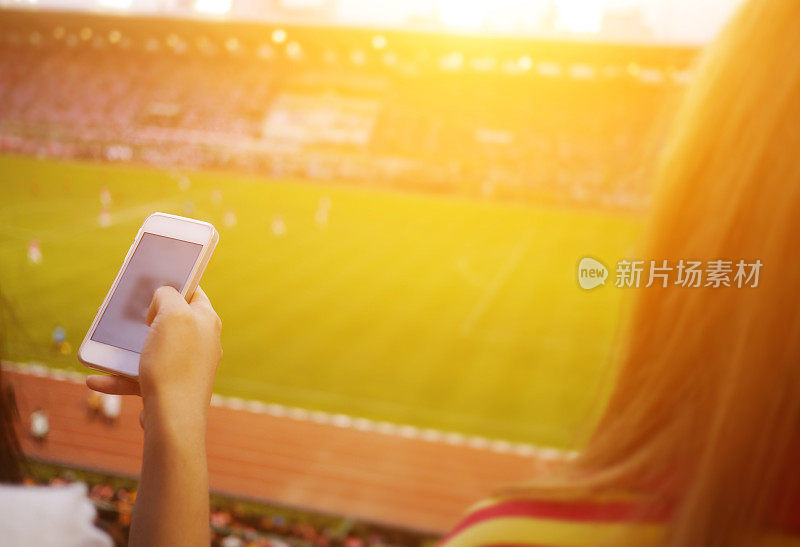 女性在足球场使用智能手机。