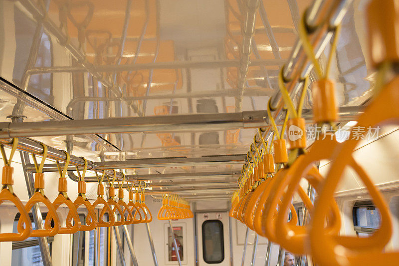 地铁里站着的乘客的橙色把手