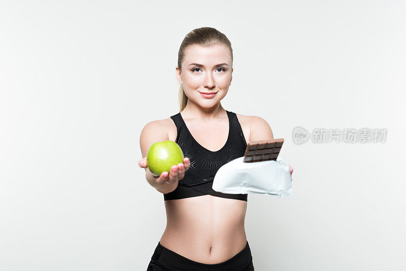 健身女子拿着苹果和白巧克力孤立在一起