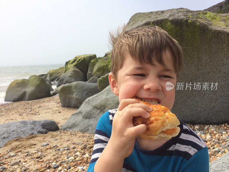 六岁男孩在海滩上吃午饭