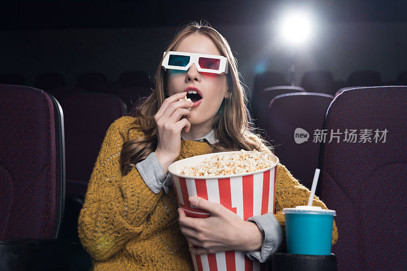 戴着3d眼镜的兴奋女人在电影院吃爆米花看电影