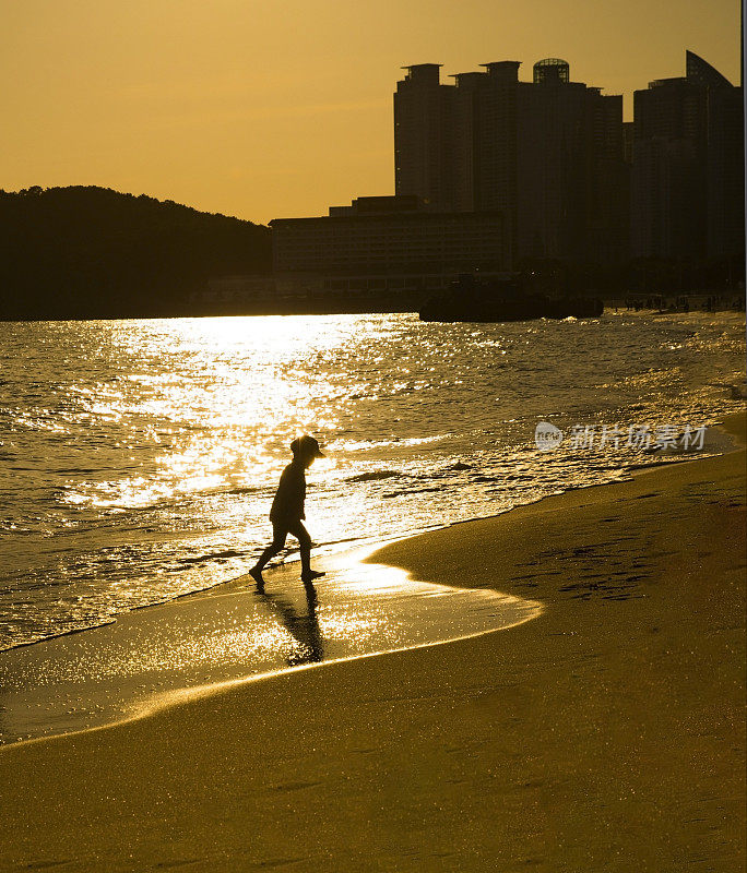 日落时在海滩上奔跑的男孩