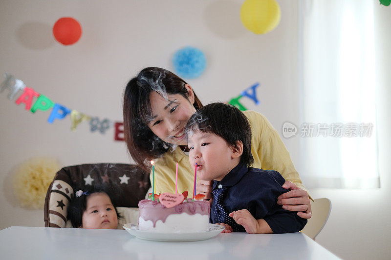 孩子吹灭生日蛋糕上的蜡烛，许他的愿望