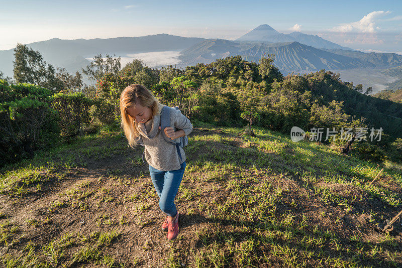 年轻女子徒步在火山景观从山顶看布罗莫火山-人们旅行冒险的概念