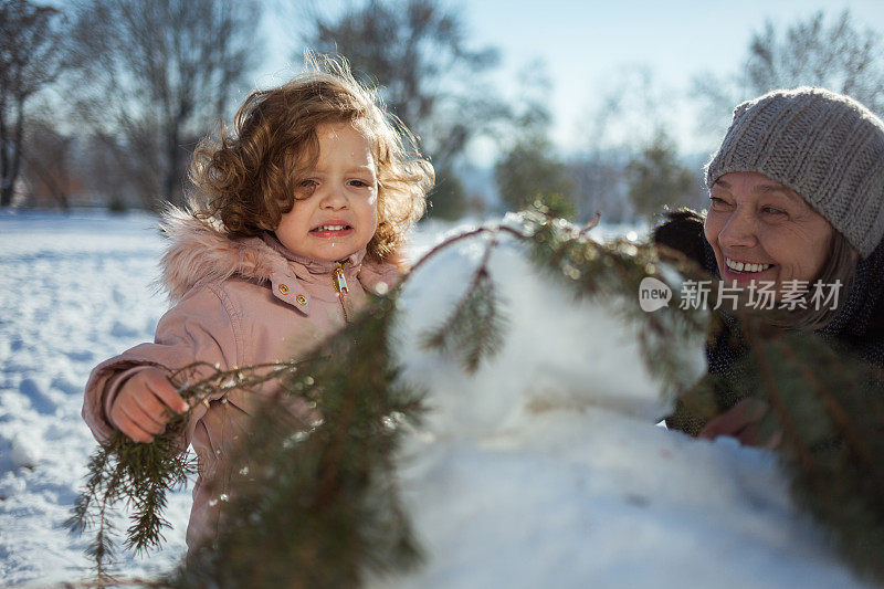 奶奶和孙女在冬天堆雪人