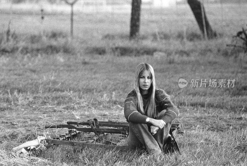 年轻女子坐在公园里。1970.