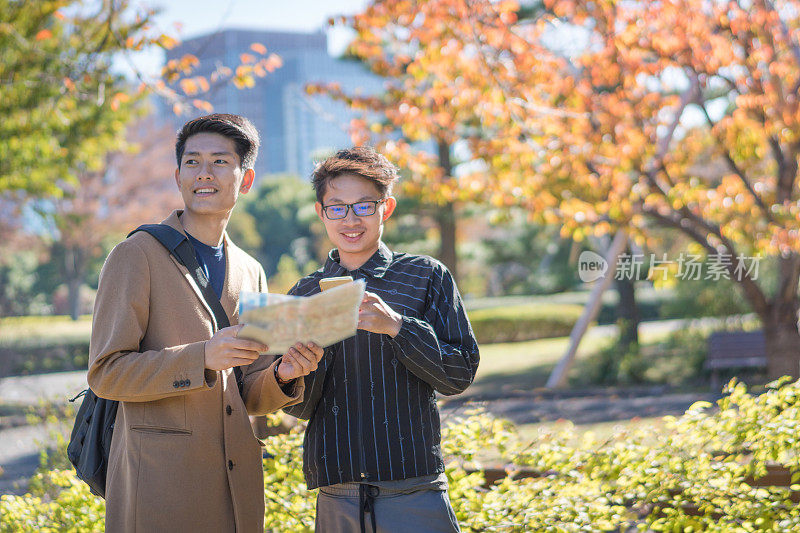 年轻的亚洲男子和日本朋友寻找旅游地点使用手机和花时间在亚洲旅行