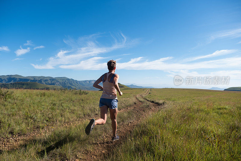 一个健康的女人在山间小路上跑步