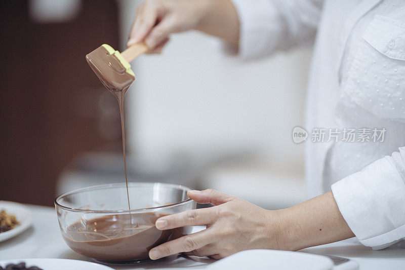 一名亚裔华人女沙漠厨师在家中准备巧克力松露，混合和报废巧克力