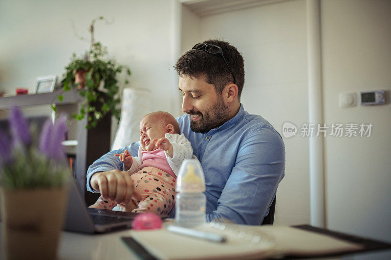 年轻的父亲和他的宝贝女儿在家里工作