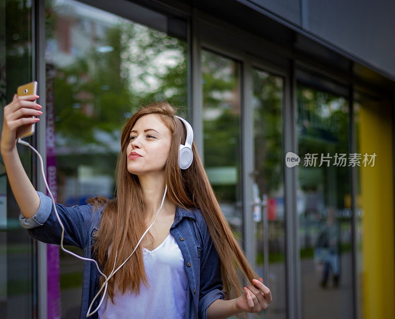 年轻迷人的女人在城市街道上自拍