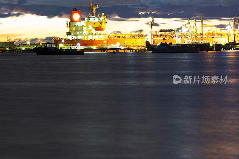 海湾在晚上与油船在炼油厂港口，背景与拷贝空间