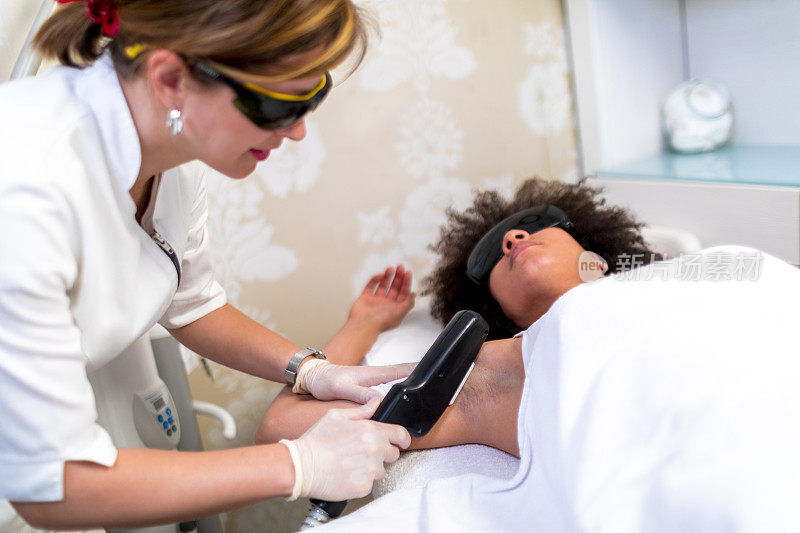 专业的美容师在美容院使用激光技术去除女性腋窝的毛发。