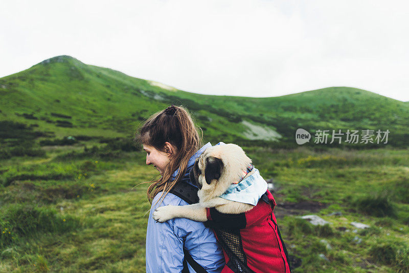 女人和狗在背包里登山