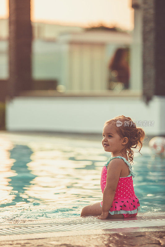 小女孩坐在泳池边享受