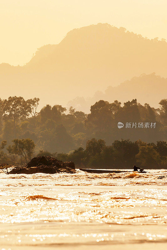 一名老挝渔民驾驶着一艘木船穿过湄公河的急流。