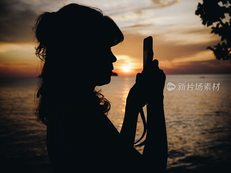 在芭堤雅海滩用智能手机发短信的快乐女人。