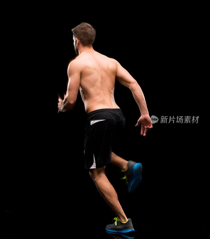 白人男性运动员穿着跑步短裤在黑色背景前跑步