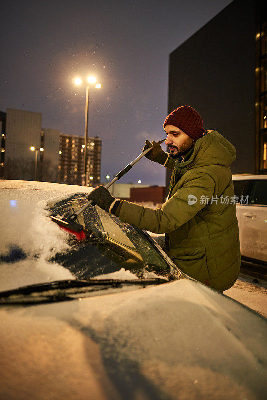 一名男子正在清除车上的积雪