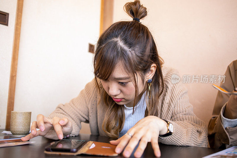 年轻女子在餐厅等午餐时使用智能手机