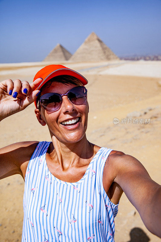 成年女子以吉萨金字塔为背景，微笑着自拍