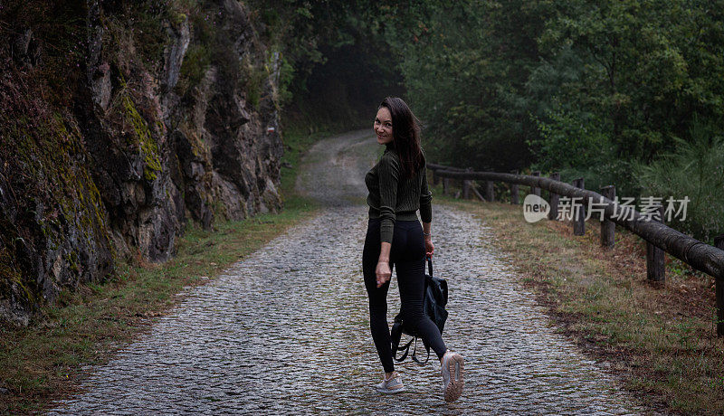 年轻女子背着背包在山里户外旅行