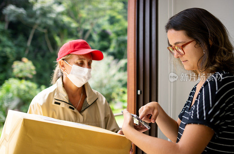 送外卖的女人戴着口罩，带着盒子去一户人家