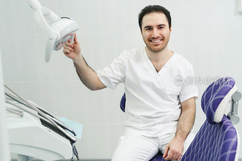 一个友好微笑的男性牙医在现代牙科诊所的办公室的肖像。